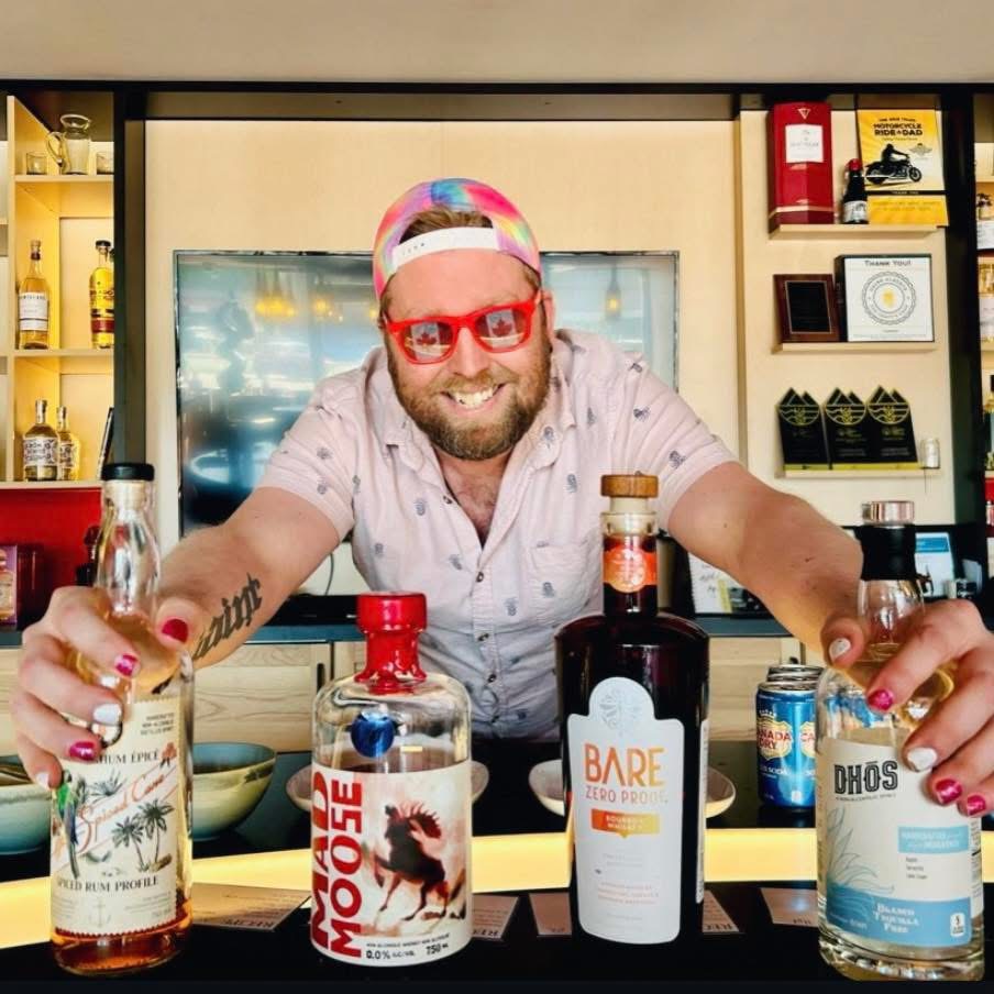 Kevin Jones smiling behind a bar with alcohol-free spirits arranged in front of him.