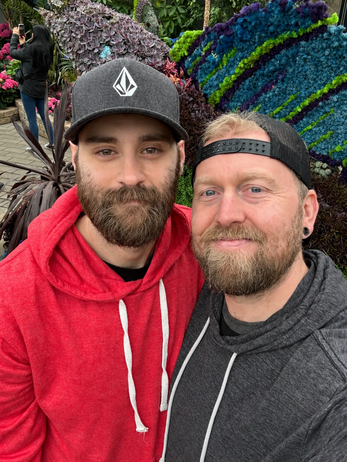 Matt and Kevin smiling together in front of a colourful garden display